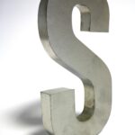 Close-up of a metallic letter S sculpture made of silver iron on a white background.